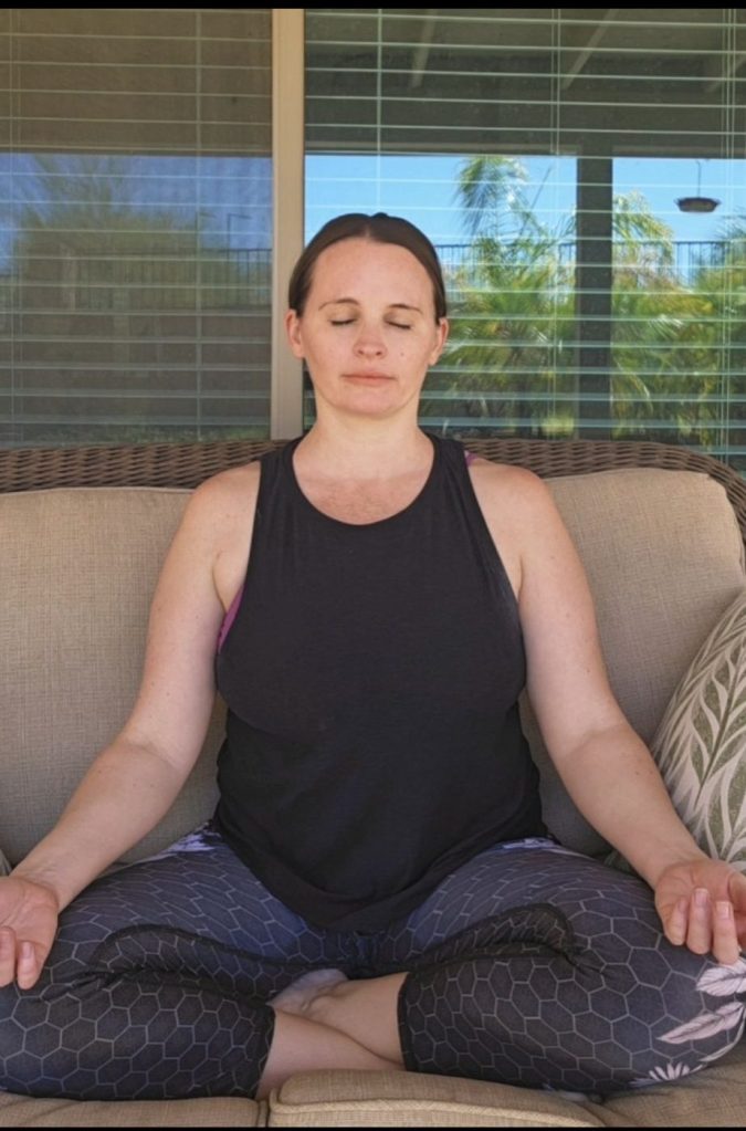 Woman meditating outdoors in seated yoga pose with eyes closed, practicing mindfulness and inner peace